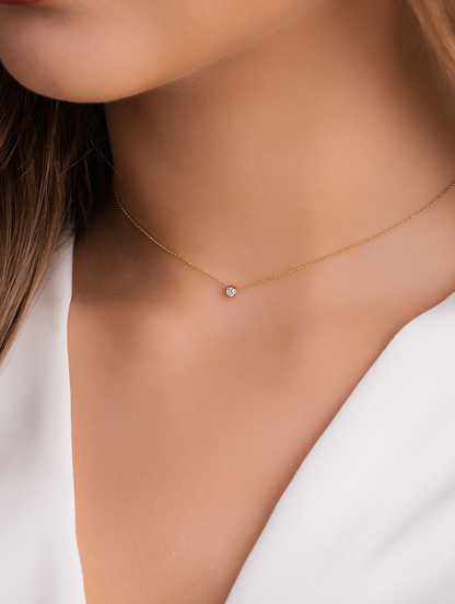 girl wearing a fine gold necklace with a bezel set diamond looking to the right